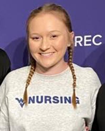Marissa is seen smiling for the camera, wearing a light gray sweatshirt with a navy flying WV and “Nursing” printed on the front.